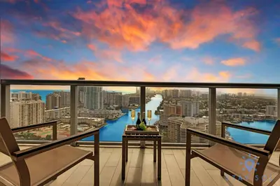a view of a city from a balcony with a table and chairs at Spacious 2BR Condo, Sleeps 6, Beachwalk Resort in Hallandale Beach