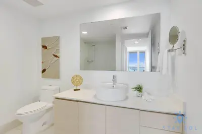 a bathroom with a sink and a toilet and a mirror at Spacious 2BR Condo, Sleeps 6, Beachwalk Resort in Hallandale Beach