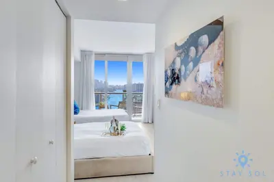 a white room with two beds and a mirror at BeachWalk Resort, Views, Balcony, Studio in Hallandale Beach
