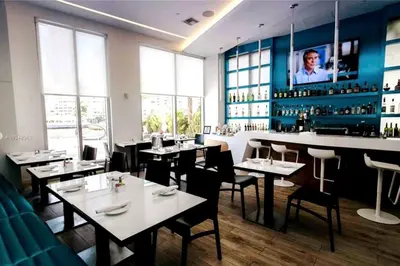 a restaurant with tables and chairs and a bar at Premium Oceanview Living Full Kitchen & Miami Chic Vibes -14 A in Hallandale Beach