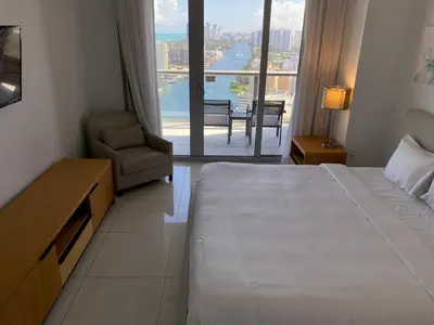 a hotel room with a bed and a chair and a window at Upscale Beach Apartment, Style, Views & Complete Kitchen -28A in Hallandale Beach
