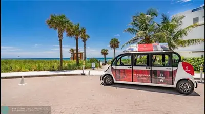 a small car parked next to a beach with palm trees at Upscale Beach Apartment, Style, Views & Complete Kitchen -28A in Hallandale Beach