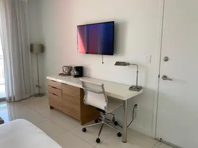 a desk with a chair and a tv on a wall at Miami Beach Glam, Ocean Views & Elegance -28B in Hallandale Beach