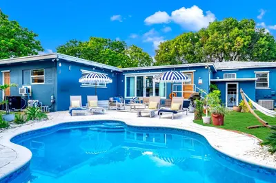 a blue house with a swimming pool and patio at Pool and Beach Relaxing Close to Everything in Dania Beach