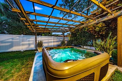 a hot tub in a backyard with a pergola at Pool and Beach Relaxing Close to Everything in Dania Beach