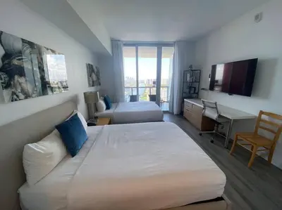 a hotel room with two beds and a desk at Beachy Vibes Studio, 2 Full Beds, Near Everything -30B in Hallandale Beach
