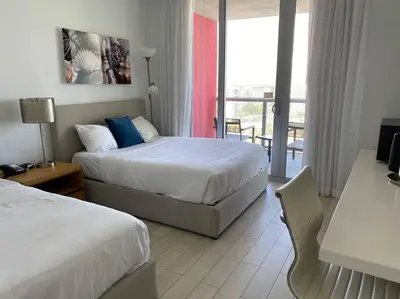 a hotel room with two beds and a balcony at Sunlit BeachWalk Studio 2 Full Beds Coastal Charm -26B in Hallandale Beach