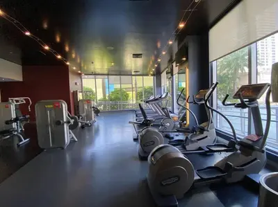 a gym with several cardio machines in a room with windows at Sunlit BeachWalk Studio 2 Full Beds Coastal Charm -26B in Hallandale Beach