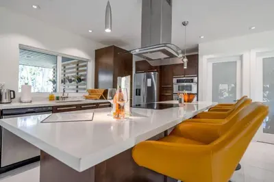 a kitchen with a white counter and orange chairs at Boho House - Stylist Home with Parking and large Yard in Miami