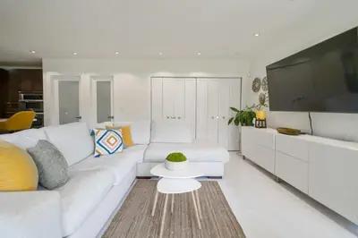 a white living room with a white couch and a tv at Boho House - Stylist Home with Parking and large Yard in Miami