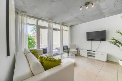 a living room with a white couch and a tv at Awesome Apt With Pool in Midtown Miami in Miami
