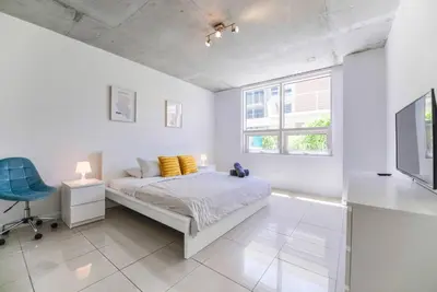 a white bedroom with a bed and a blue chair at Awesome Apt With Pool in Midtown Miami in Miami