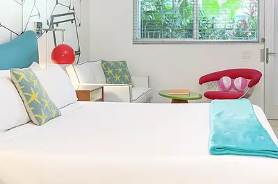a bedroom with a large white bed and a red chair at The Vagabond Hotel Miami in Miami