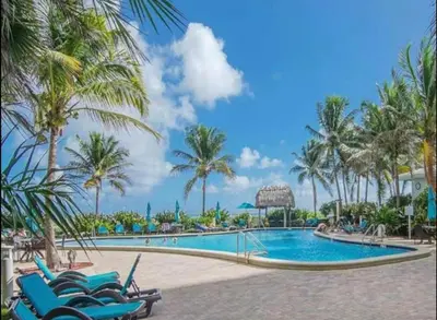 a pool at a resort with chairs and palm trees at The Tides! On the beach, Sea view! in Hollywood