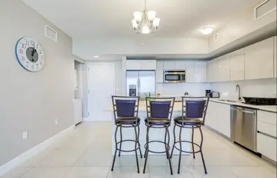 a kitchen with white cabinets and bar stools at Stunning Penthouse Suite Waterfront 2BD 2BA in Hallandale Beach