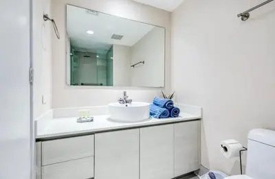 a white bathroom with a sink and a mirror at Stunning Penthouse Suite Waterfront 2BD 2BA in Hallandale Beach