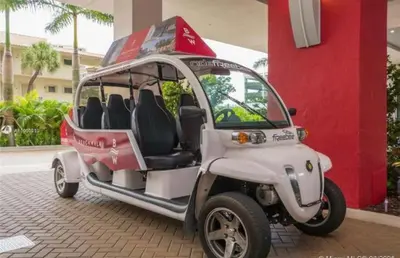 a small white golf cart parked in front of a building at Stunning Penthouse Suite Waterfront 2BD 2BA in Hallandale Beach