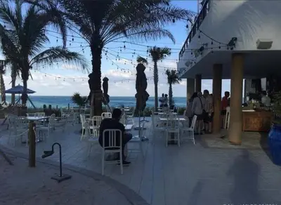 a group of people sitting at tables on the beach at Stunning Penthouse Suite Waterfront 2BD 2BA in Hallandale Beach