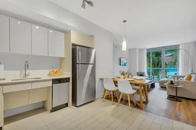 a kitchen and living room with a table and a refrigerator at Apartment with Balcony, Gym & Near Beach in Hallandale Beach