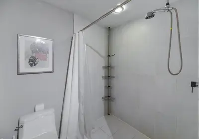 a white bathroom with a shower and a toilet at Amazing Condo with Pool at Midblock Miami in Miami