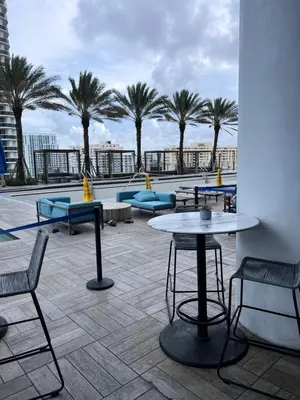 a patio with tables and chairs and palm trees at Lyfe Oceanview Resort Luxury 2 Bedroom Unit in Hollywood