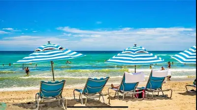 a group of chairs and umbrellas on a beach at Chic Beach Studio Walk to Shore Sleeps 4 -14B in Hallandale Beach