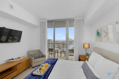 a bedroom with a bed and a television and a balcony at Infinite View - Balcony- Amazing Pool- Near Beach in Hallandale Beach
