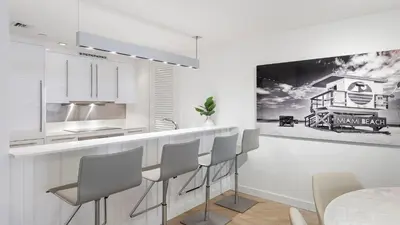 a white kitchen with a bar with stools at Ocean View Private Residence at South Beach - 804 in Miami Beach
