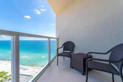 two chairs on a balcony overlooking the ocean at 16699 Collins Ave Unit 2906 in La Perla in Miami Beach