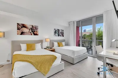 a bedroom with two beds and a desk and a balcony at MODERN Resort Modern apartment 2 BR 2 BR POOL in Hallandale Beach