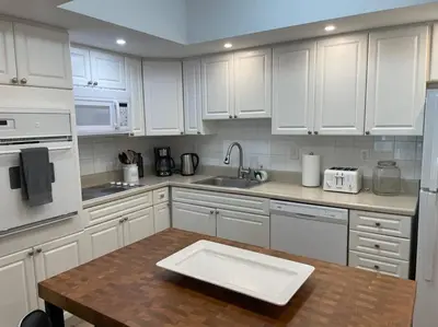 a kitchen with white cabinets and a wooden table at Ocean Reserve 222 STR-2158 in Miami Beach