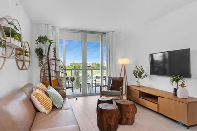 a living room with a couch and a flat screen tv at Tropical Apartment with Balcony - Pool - Up To 4 - Gym in Hallandale Beach