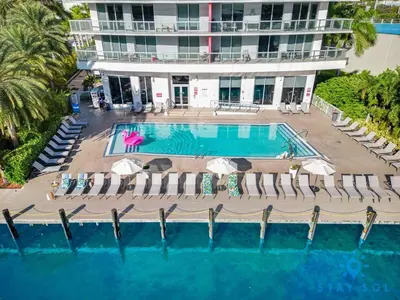 an aerial view of a pool with chairs and a building at Tropical Apartment with Balcony - Pool - Up To 4 - Gym in Hallandale Beach