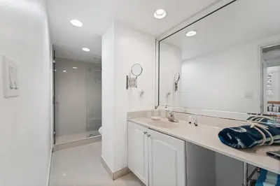 a white bathroom with a sink and a mirror at Oceanfront Luxury Condo - Private Beach Access, Pool & Game Room in Hollywood