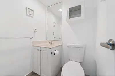 a white bathroom with a toilet and a sink at Oceanfront Luxury Condo - Private Beach Access, Pool & Game Room in Hollywood