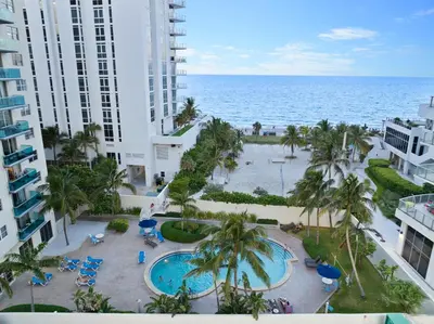 an aerial view of a resort with a pool and the ocean at Oceanfront Luxury Condo - Private Beach Access, Pool & Game Room in Hollywood