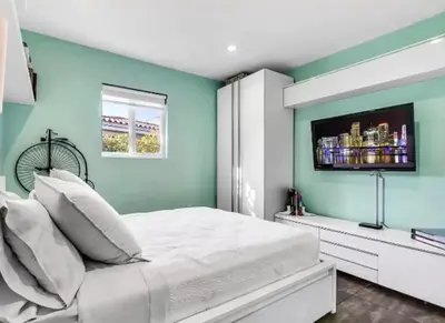 a bedroom with a white bed with a tv on the wall at Modern Northwest Vacation Rentals in Miami in Miami