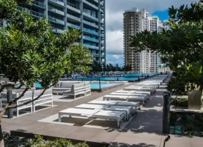 a row of white chaise lounges next to a pool at Vacation Apartment in Miami in Miami