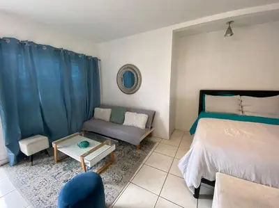a bedroom with a bed and a couch and a table at Small House Near Airport Beach - Wynwood in Miami