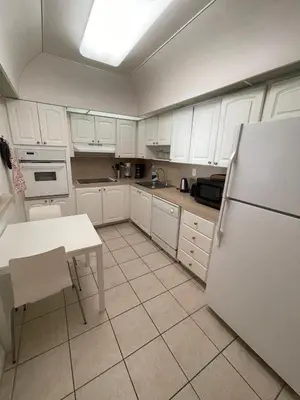 a kitchen with white cabinets and a table and a refrigerator at Ocean Reserve 207 - STR 2270 in Miami Beach