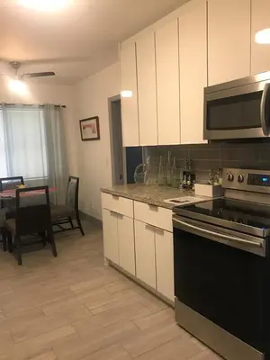 a kitchen with white cabinets and a black stove top oven at Bekahouse Hostel with parking, backyard and laundry in Miami