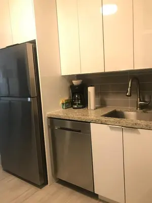 a kitchen with white cabinets and a stainless steel refrigerator at Bekahouse Hostel with parking, backyard and laundry in Miami