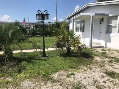 a house with palm trees and a light pole in the yard at Bekahouse Hostel with parking, backyard and laundry in Miami