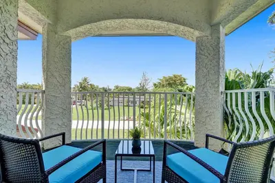 a porch with two chairs and a table and a balcony at Spacious home wprivate pool game room in Plantation