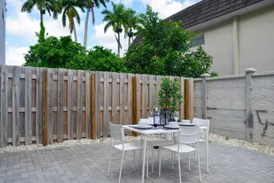 a table with white chairs and a fence at Awesome 3BR Townhouse 15minutes from the Beach in Miami
