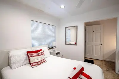 a bedroom with a white bed with red and white pillows at B efficiency Off Las Olas on water free kayaks in Fort Lauderdale