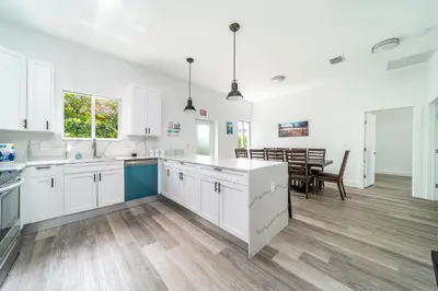 a kitchen with white cabinets and a dining room at Pool Boutique Villa by the Beach 1 in Hallandale Beach