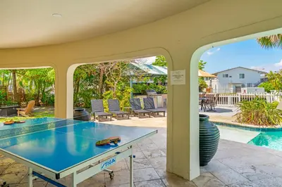 a ping pong table on a patio next to a pool at Waterfront Retreat: 7BR Villa with Pool Firepit in Fort Lauderdale