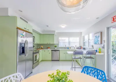 a kitchen with green cabinets and a table and chairs at Fun Family-Friendly Poolside Escape Near Beach in Dania Beach