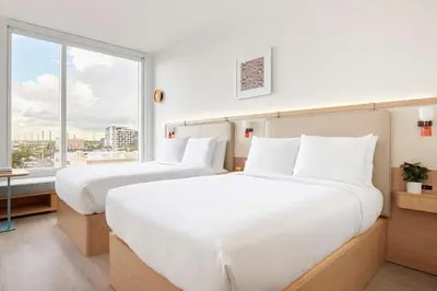 two beds in a hotel room with a large window at Arlo Wynwood Miami in Miami